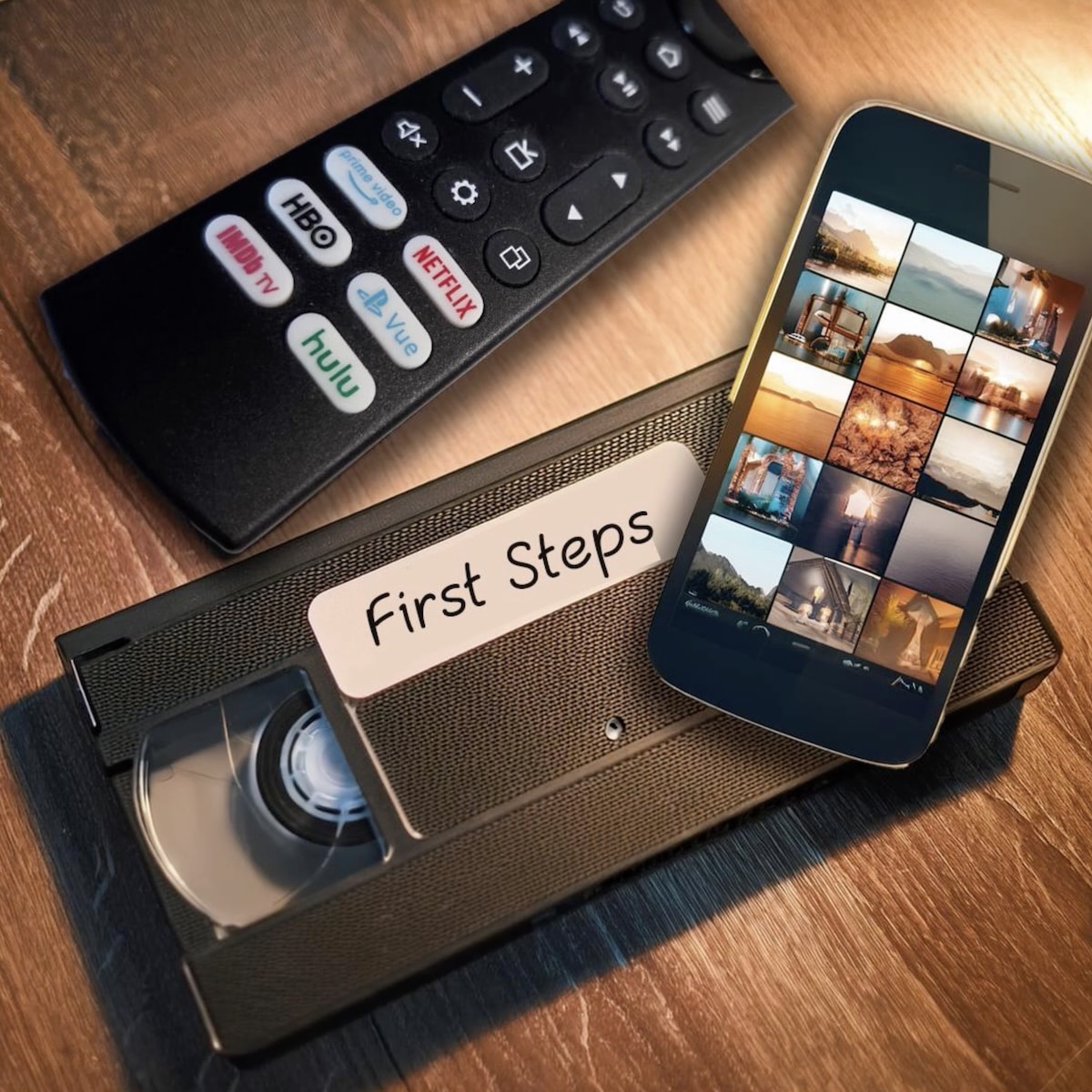 A VHS tape labeled First Steps, a phone displaying special moments in photo thumbnails, and a TV remote with streaming service buttons sit on a wooden surface.